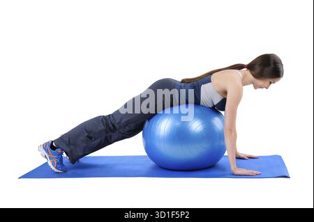 Junge Frau zeigt Startposition des Fitness Stability Ball Glute Kickback Workouts, isoliert auf weiß Stockfoto