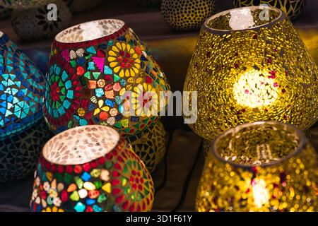 Türkische Mosaikglaslampen leuchten in einer dunklen Umgebung, ihre aufwendigen handgefertigten Muster erzeugen warmes, farbenfrohes Licht und verzierten, traditionellen Charme per Stockfoto