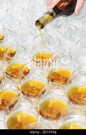 Gießen Sie den Brandy oder Cognac in Gläser in Reihen Stockfoto