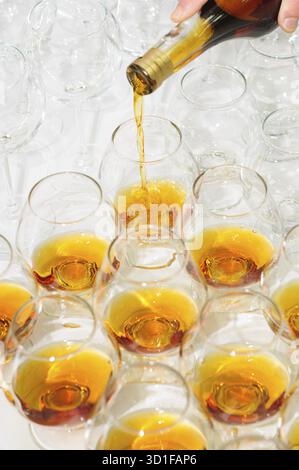 Gießen Sie den Brandy oder Cognac in Gläser in Reihen Stockfoto