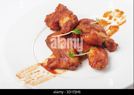 Gebratene Hähnchenschenkel in roter, scharfer Karamellsauce mit grünen Bohnensprossen auf weißem Teller Stockfoto