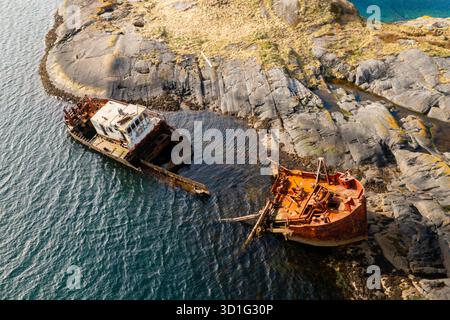 Wrackteile eines versunkenen Schiffes in der Nähe der felsigen Küste Norwegens, umgeben von kalten Nordgewässern und dramatischen Klippen. Stockfoto