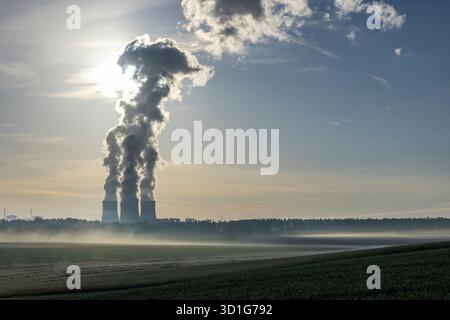 Kernkraftwerksschornsteine, die Dampf in den sonnigen Himmel über einer nebeligen Landschaft in Driten, Tschechien, abgeben Stockfoto