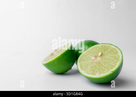 Frische grüne Limetten, ganz und in Hälften geschnitten. Isoliert auf einem sauberen weißen Hintergrund. Gesunde Zitrusfrüchte. Viel Kopierraum links. Stockfoto