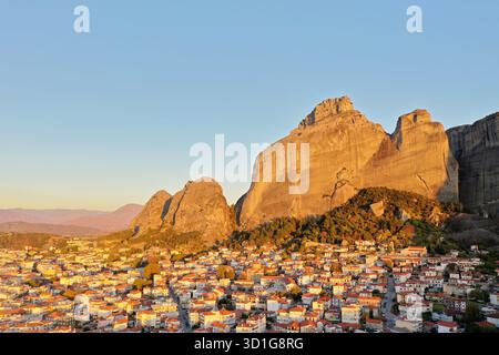 Drohnenblick auf Kalabaka und die Meteora Felsformationen in Griechenland, beleuchtet durch warmes Morgenlicht, mit traditionellen Häusern und dramatischen Klippen in Th Stockfoto