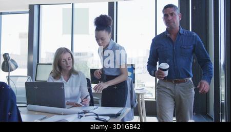 Mitarbeiter, die Dokumente überprüfen, auf einen Plan in der Nähe eines Notebooks in modernen Büros zeigen Stockfoto