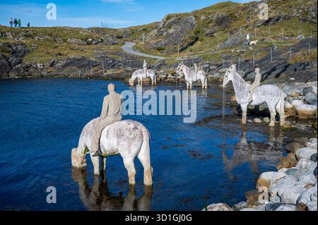 In der ruhigen Landschaft des Rising Tide, Haugesund, Norwegen, kann eine Person auf einem Pferd aus einem ruhigen Gewässer trinken, umgeben von Hor-Statuen Stockfoto