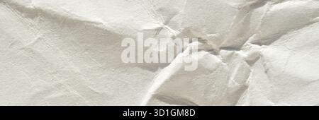Nahaufnahme zerknitterter weißer Papierstruktur mit detaillierten Falten und Falten bei weicher Beleuchtung. Stockfoto