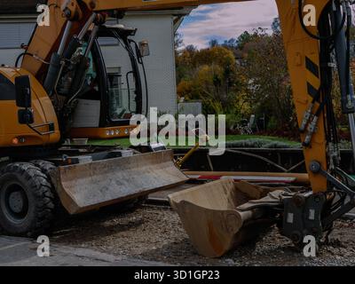 Großer gelber Bagger für den Bau von Stadtstraßen, das Graben von Boden und die Reparatur von Asphalt während der Instandhaltung der städtischen Infrastruktur. Profi-Foto. Hoch Stockfoto