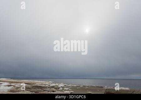 Die helle Sonne scheint wunderschön durch die flauschigen Wolken, die über dem riesigen Ozean hängen, und schafft eine malerische Szene Stockfoto