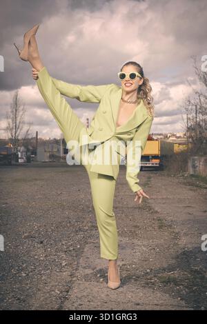 Hübsche Dame in grünem Kostüm posiert auf Industriestandort Stockfoto