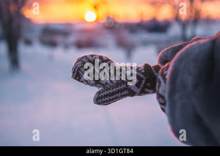 Eine Person trägt ein warmes und gemütliches Paar Handschuhe, während sie an einem kühlen Tag im wunderschönen, weichen Schnee um sie herum spielt Stockfoto