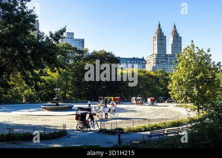 Pferde- und Kutschpassagiere am Cherry Hill Fountain im Central Park, Manhattan, New York City, mit dem San Remo Gebäude im Hintergrund Stockfoto