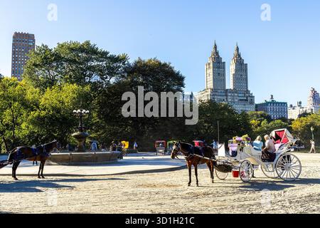Pferde- und Kutschpassagiere am Cherry Hill Fountain im Central Park, Manhattan, New York City, mit dem San Remo Gebäude im Hintergrund Stockfoto