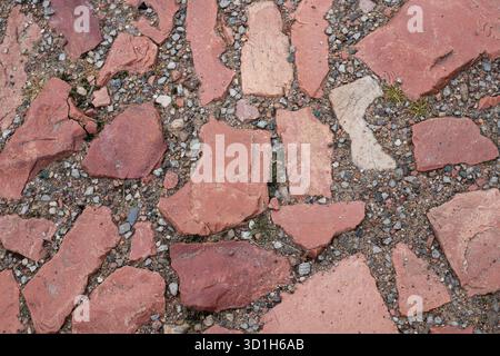 Alte Straße aus roten Granitziegeln, ein Blick aus der Nähe von oben. Alte Ziegelsteinpflasterstraße mit großen Steinen Stockfoto