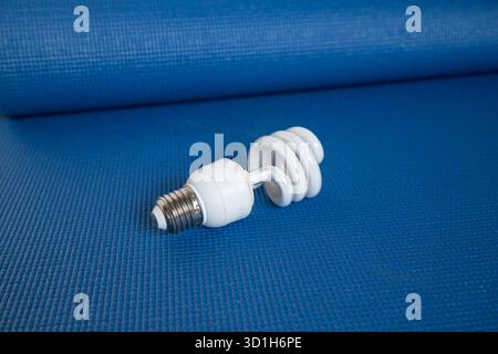 Energiesparende kompakte Leuchtstofflampe auf blauem texturiertem Hintergrund Stockfoto