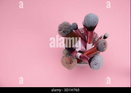 Make-up-Bürsten stehen in einem Halter vor rosa Hintergrund. Stockfoto