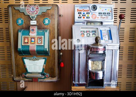 ANTIKE EINARMIGE BANDITEN, SPIELAUTOMATEN: Ein Display zeigt zwei antike Münzautomaten mit drei Rollen. Das eine ist ein finnisches Modell, das finnische Marken als Währung verwendete. Einer ist Amerikaner, der Cent benutzt. Stockfoto