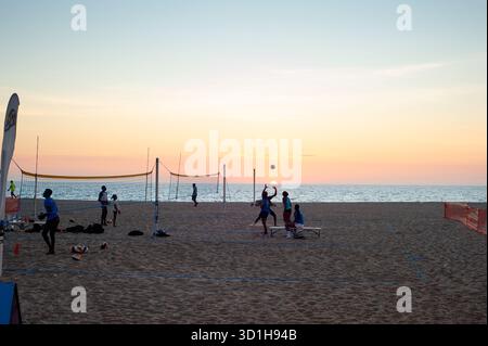 LUANDA, ANGOLA - 29. APRIL 2025: Menschen spielen Volleyball am Strand von Ilha de Luanda bei Sonnenuntergang Stockfoto