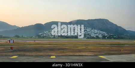 Doloman, Türkei - 25. April 2025: Malerisches Dorf am Hügel mit weißen Gebäuden vor einer Bergkulisse. Stockfoto