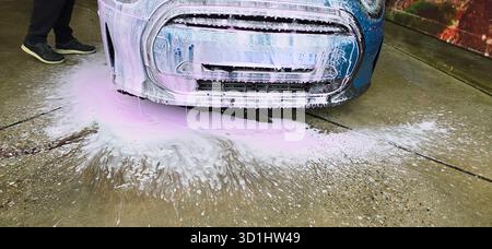 Berlin, Deutschland - 18. Mai 2025: Das Auto wird mit Schaum und Wasser auf dem Bürgersteig im Freien gewaschen. Stockfoto