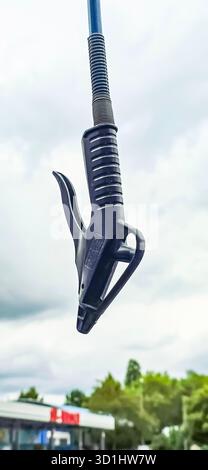 Berlin, Deutschland - 18. Mai 2025: Kraftstoffdüse hängt an der Pumpe mit bewölktem Himmel im Hintergrund. Stockfoto