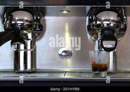 Cremona, Italien - 21. Juli 2025 Nahaufnahme von Barista, der Espresso Shot in transparenter Tasse aus einer professionellen Kaffeemaschine mit Chromfinish und zubereitet Stockfoto