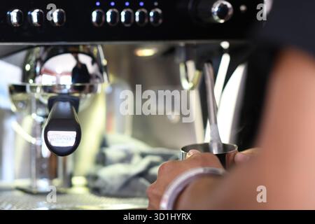 Cremona, Italien - 21. Juli 2025 der erfahrene Barista schäumt fachmännisch Milch für die perfekte Zubereitung von Latte Art in einem modernen Coffee Shop auf Stockfoto