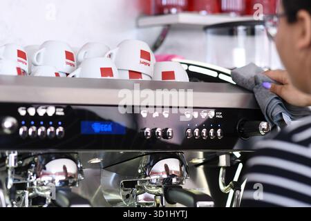 Cremona, Italien - 21. Juli 2025 Barista Reinigung professionelle Espressomaschine mit Tuch im Café professionelle Kaffeemaschine Maintena Stockfoto