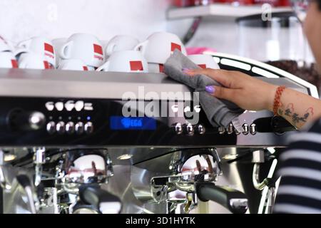 Cremona, Italien - 21. Juli 2025 professionelle Barista Reinigung und Polieren einer kommerziellen Espressomaschine mit einem Mikrofasertuch zur Gewährleistung der Hygiene und des Polierens Stockfoto