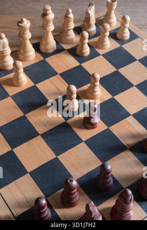 Holzschachbrett mit hellen und dunklen Schachfiguren in einer Mitte des Spiels, die Strategie und intellektuelle Herausforderung hervorheben. Stockfoto