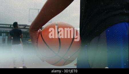 Spieler in Sportbekleidung, der Basketball auf dem Dach hält, mit Korb und transparentem Rückenbrett Stockfoto