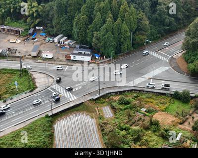 Eine geschäftige Kreuzung mit Autos und Lastwagen auf der Straße. Die Kreuzung ist von Bäumen und Gebäuden umgeben Stockfoto
