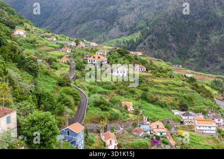 Charmante traditionelle Häuser eingebettet in die üppigen grünen Hügel der Insel Madeira, Portugal, mit gewundenen Straßen und malerischen Landschaften. Stockfoto