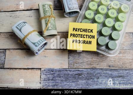 Konzept des Gehaltsscheck-Schutzprogramms Schreiben Sie auf Haftnotizen, die auf Holztisch isoliert sind. Stockfoto