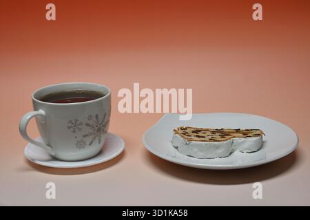 Stollen und weiße Tasse schwarzen Tee mit Schneeflocken Stockfoto