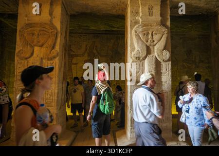 Touristen erkunden das Innere des Tempels von Hathor und Nefertari, geschmückt mit Hieroglyphen und geschnitzten Steinsäulen, Abu Simbel, Ägypten Stockfoto