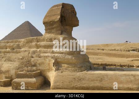 Seitenansicht der Großen Sphinx von Gizeh mit einer Pyramide im Hintergrund unter einem klaren blauen Himmel in Ägypten Stockfoto