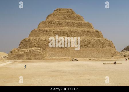 Pyramide von Djoser - antike Stufenpyramide, die unter einem klaren blauen Himmel aus der Wüste aufsteigt und die frühägyptische Architektur in Memphis, Ägypten, zeigt Stockfoto