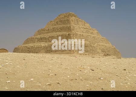 Pyramide von Djoser - antike Stufenpyramide, die unter einem klaren blauen Himmel aus der Wüste aufsteigt und die frühägyptische Architektur in Memphis, Ägypten, zeigt Stockfoto
