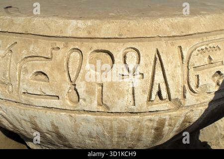 Nahaufnahme eines antiken ägyptischen Steinartefakts mit detaillierten Hieroglyphenschnitzereien auf einer gekrümmten Oberfläche Stockfoto