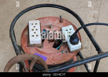 Eine alte, umgebaute Steckdose mit unheimlichen Drähten und rostigem Metall sieht nicht sicher aus. Stockfoto