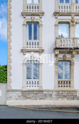 Weiße Putzfassade mit kunstvoll geschnitzten Steinfenstern und Balkon in traditioneller europäischer Architektur Stockfoto