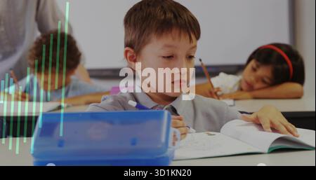 Schreibjunge mit Schwerpunkt auf Arbeitsbuch am Schreibtisch im Klassenzimmer, mit blauem Bleistiftetui und Zubehör Stockfoto