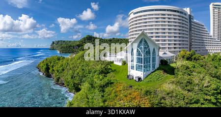 Ein atemberaubender Blick auf die Kristallkapelle im Hotel Nikko in Tumon Bay, Guam, mit zwei Liebenden in der Ferne. Dieses Drohnenfoto macht es Stockfoto
