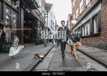 Magic, ein sieben Monate alter Golden Retriever Cross Labrador Welpe, besucht die Shambles in York mit dem ehrenamtlichen Welpen Raiser Nadine Field, als Teil eines speziellen Trainingstages mit Begleithunden, um an Halloween Vertrauen in geschäftigen Straßen, Kostümen und Dekorationen aufzubauen. Ausgabedatum: Mittwoch, 29. Oktober 2025. Stockfoto