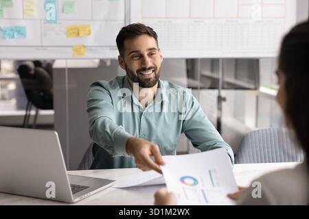 Ein lächelnder Finanzanalytiker gibt der Führungskraft einen Bericht Stockfoto