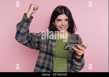 Junge Frau, die Erfolg feiert, während sie ein Smartphone hält. Stockfoto