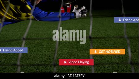 Torhüter mit Handschuhen, der auf dem Rasenplatz in der Nähe des Netzes mit UI-Overlays einen sicheren Versuch macht Stockfoto