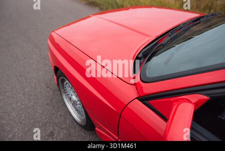 Kotflügel vorn und Motorhaube des roten Autos. Weitwinkel-Nahaufnahme des vorderen Teils des roten Kompaktwagens. Stockfoto
